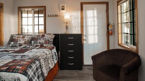 Quarto com cama, cômoda, cadeira, ventilador de teto e janela.