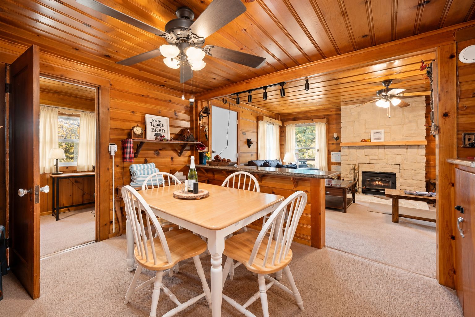 Un intérieur en bois comprenant un coin repas, une cheminée et un ventilateur de plafond.