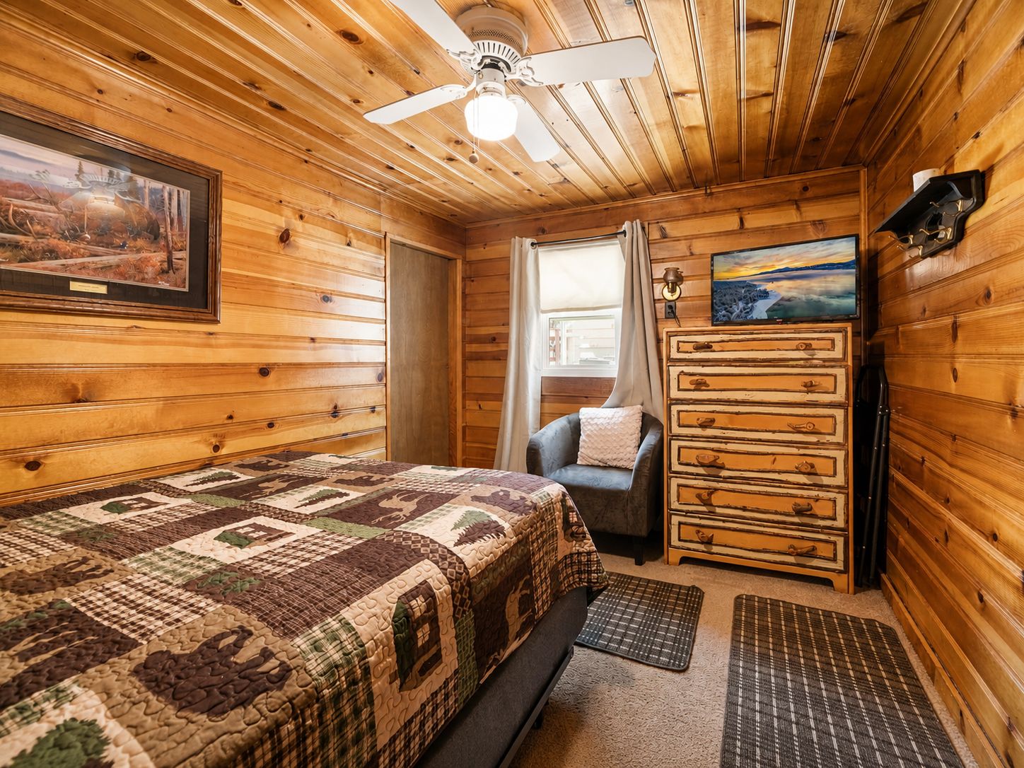 Une pièce confortable avec un lit, une chaise, une commode et un ventilateur de plafond.