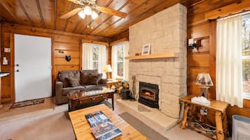 L’intérieur d’un chalet accueillant, avec une cheminée, des murs en bois, un canapé et une table basse.
