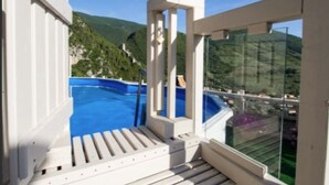A balcony with a pool, white railings, and a view of green hills. - LE ROCCHE - Under the Castle, SMERALDO Apartment with SPA and Black River View (Ferentillo)
