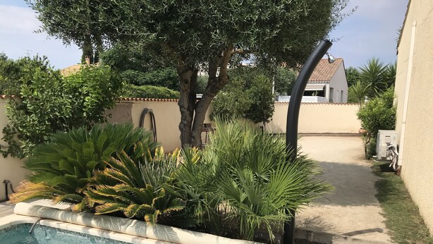 A swimming pool surrounded by lush greenery and a clear blue sky. - House with garden and pool near CAP D'AGDE (Agde)