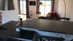 A modern kitchen with a large island, dining area with chairs and a table, and a TV mounted on the wall. - House with garden and pool near CAP D'AGDE (Agde)
