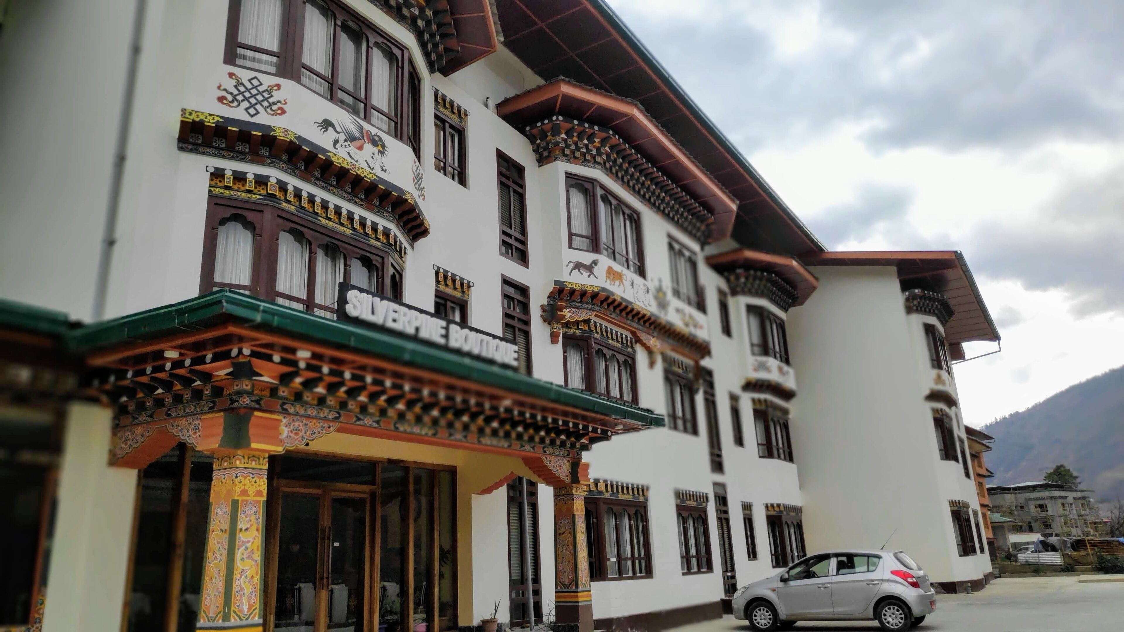 A traditional building with ornate architectural details, a sign for 'Silverpine Boutique', and a parked car in front.