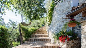 A stone staircase leading up to a rustic stone building with a flower pot on the right.