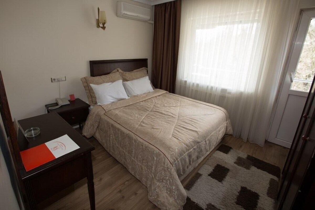 Una habitación de hotel con cama, mesita de noche y escritorio con silla.