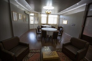Un salón de conferencias con una mesa redonda, sillas y una araña.