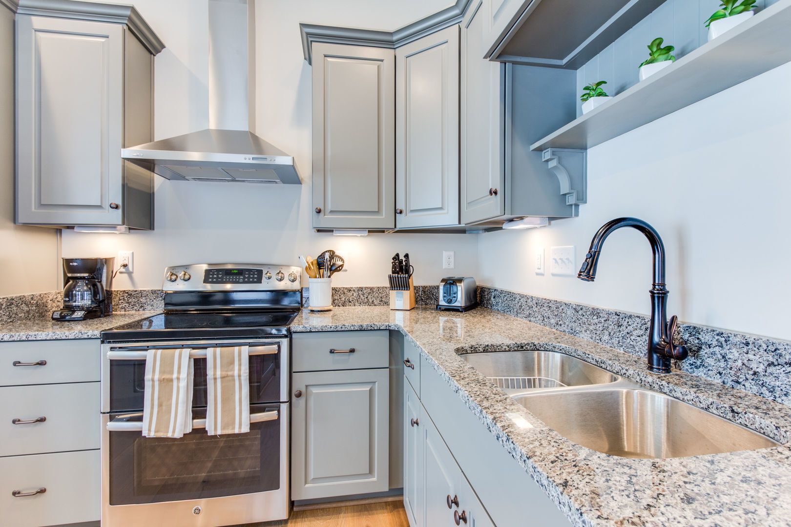 A modern kitchen with granite countertops, stainless steel appliances, and white cabinetry.