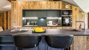 Ett modernt kök med träpanel på väggarna, en svart bänkskiva, en diskho och en inbyggd ugn.