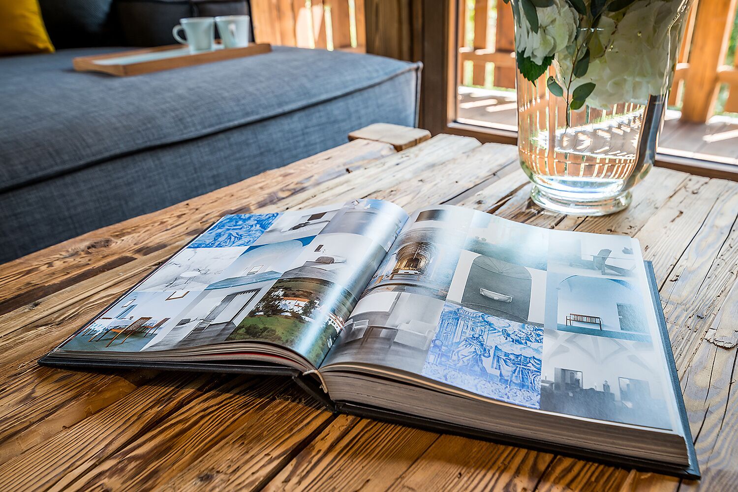 An open magazine with architectural photos on a wooden table.