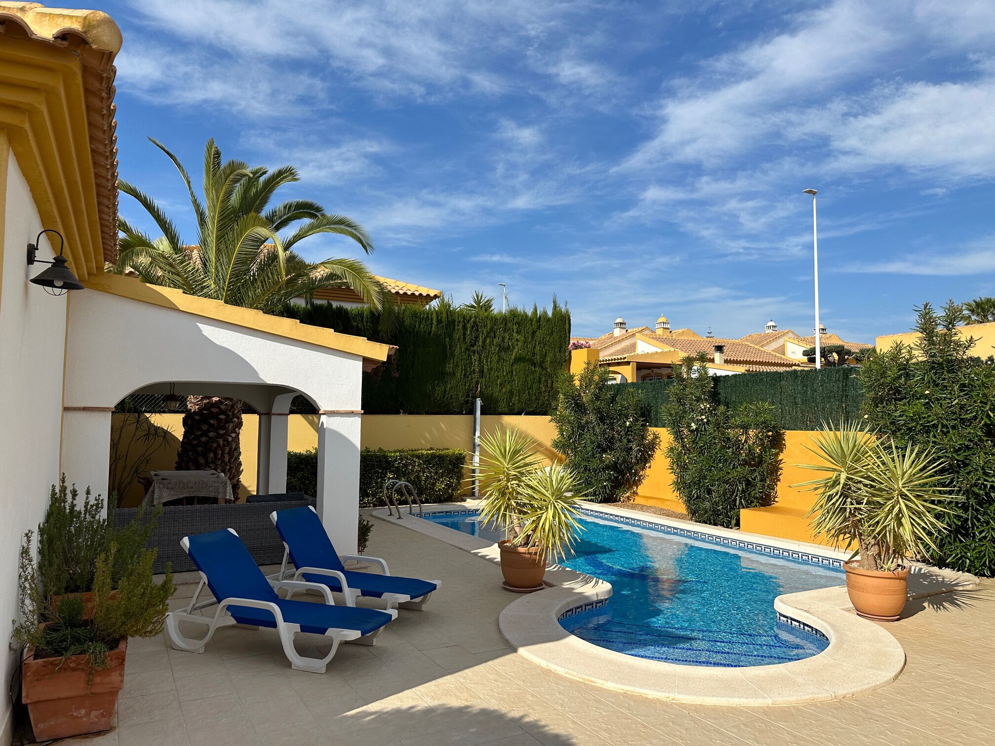 A pool area with lounge chairs, a small pool, and surrounding greenery.