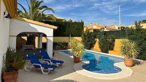 Ein Poolbereich mit Liegestühlen, einem kleinen Pool und umliegender Bepflanzung.