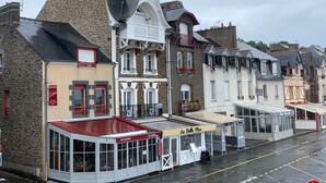 Eine Reihe traditioneller Gebäude im europäischen Stil mit steinernen Fassaden und Satteldächern, darunter verschiedene Geschäfte und Restaurants.
