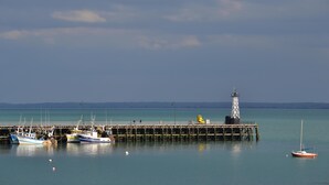 Eine Steg mit anliegenden Booten, ein Leuchtturm und ruhiges Wasser.