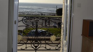 Ein Zimmer mit Meerblick, der sich durch einen Balkon mit Metallgeländer und einer Blumenanordnung zeigt.