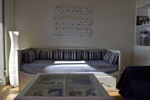 Une pièce comprenant un canapé, une vitrine contenant divers objets et un mur orné de texte.