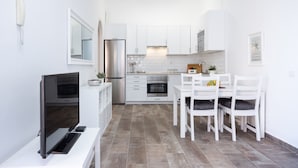 A modern kitchen with white cabinetry, a built-in oven, and a dining area with white chairs and a table. - Romantic Retreat In Prime Position With Stunning Views (Santiago del Teide)