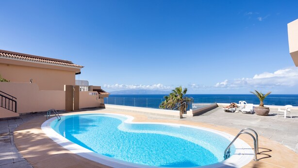 A swimming pool with a view of the ocean, surrounded by lounge chairs and a palm tree. - Romantic Retreat In Prime Position With Stunning Views (Santiago del Teide)