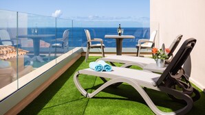 A balcony with a glass railing, two lounge chairs, a small table with a bottle and glass, and a potted plant. - Romantic Retreat In Prime Position With Stunning Views (Santiago del Teide)