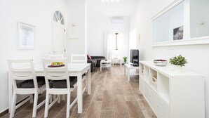 A modern, white-themed living room with a dining area, a sofa, and a TV on a white console. - Romantic Retreat In Prime Position With Stunning Views (Santiago del Teide)