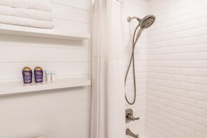 Een bad/douchecombinatie, een haardroger, handdoeken, zeep