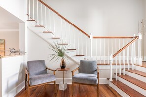 Stairs lead up to a cozy seating area with armchairs and a small table.