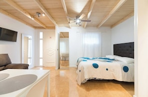 Une chambre à coucher avec un lit, un téléviseur et un ventilateur de plafond.