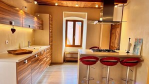 Een moderne keuken met houten kasten, een centraal eiland met krukken en een zichtbare kookplaat.
