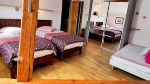 Een slaapkamer met twee bedden, houten vloeren en een schuifglazen deur die naar een andere kamer leidt.
