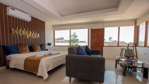 Een moderne hotelkamer met een bed, een bank, een glazen salontafel en grote ramen met uitzicht op de stad.