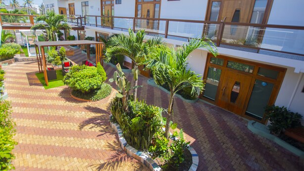 Een hotel met een overdekt terras, meerdere balkons en diverse beplanting.