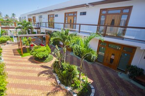 A hotel with a covered outdoor area, multiple balconies, and a variety of plants. - Hotel Blue Marlin (Puerto Baquerizo Moreno)