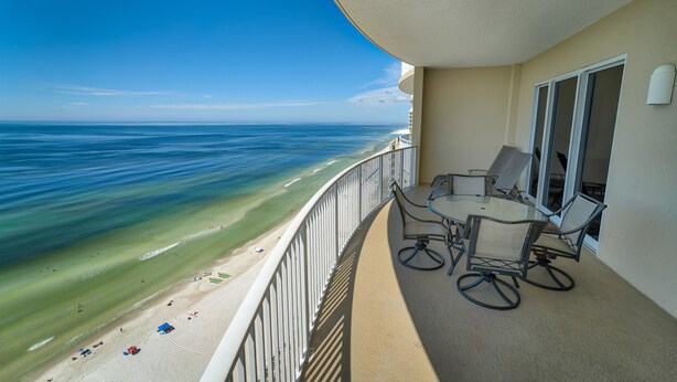 A balcony with a view of the beach and ocean.