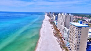 A coastal cityscape with a beachfront hotel adjacent to a sandy beach and the ocean.