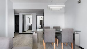 Un espace repas moderne avec une table en verre, des chaises grises à revêtement en tissu et des pieds en bois.