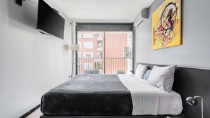 Une chambre à coucher moderne avec un lit, un téléviseur fixé au mur et un tableau.