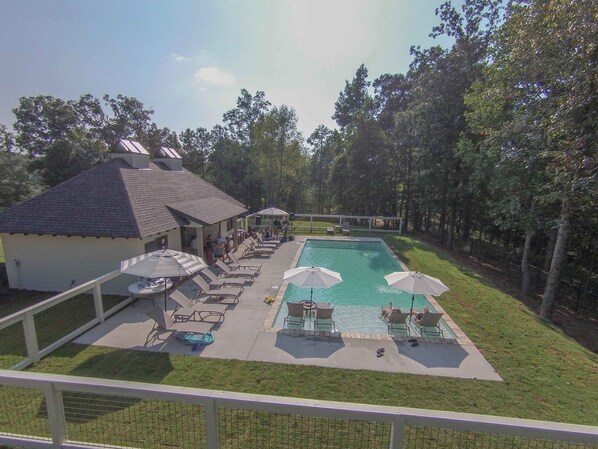 A pool area with lounge chairs and umbrellas, surrounded by trees and a building with a sloped roof. - Exclusive Smith Lake Slice of Heaven  in the Gated Point William Development.  (Crane Hill)