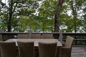 A deck with a table and chairs, surrounded by trees and overlooking a body of water. - Exclusive Smith Lake Slice of Heaven  in the Gated Point William Development.  (Crane Hill)