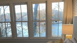 A bedroom with a large bed, multiple windows, and a view of trees and a snowy landscape. - Exclusive Smith Lake Slice of Heaven  in the Gated Point William Development.  (Crane Hill)