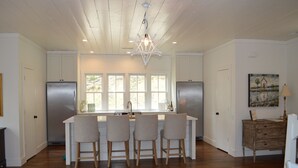 A modern kitchen with a central island, wooden bar stools, and a hanging light fixture. - Exclusive Smith Lake Slice of Heaven  in the Gated Point William Development.  (Crane Hill)