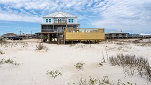 A beachfront house with a wooden deck and a staircase leading to the main entrance. - Gulf Front Home with 3 Master Bedrooms (Dauphin Island)