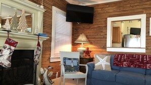 Un soggiorno accogliente con camino, televisore a parete, un divano blu e una decorazione a stella marina.