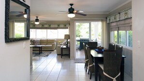 Amplia sala de estar con mesa de comedor, sillas, sofá y ventilador de techo.
