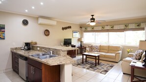 Una cocina con encimeras de granito, lavavajillas y un comedor con sofá y mesa de centro.