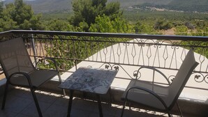 En balkon med et bord og stole med udsigt over et bjerglandskab.