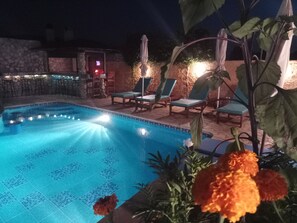 A swimming pool with lounge chairs and umbrellas, surrounded by stone walls and plants. - Guest House Kithairon (Mandra-Eidyllia)