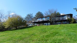 A two-story building with a balcony on the upper floor, surrounded by trees and a grassy area. - Berkshire Mountain House (Stephentown)