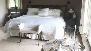 A bedroom with a large bed, a chair, a table set for dining, and a painting on the wall. - Berkshire Mountain House (Stephentown)