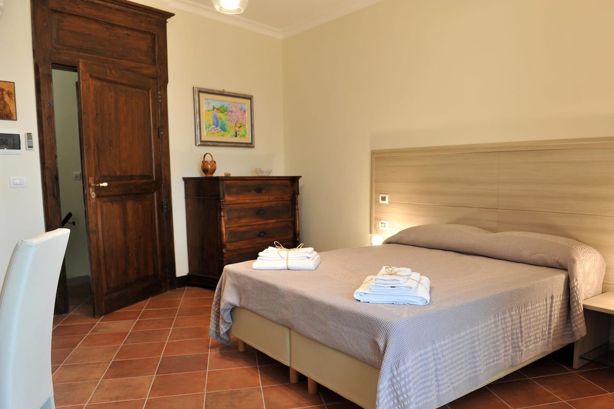 Une chambre à coucher avec un lit, des tables de chevet, une commode et une porte.