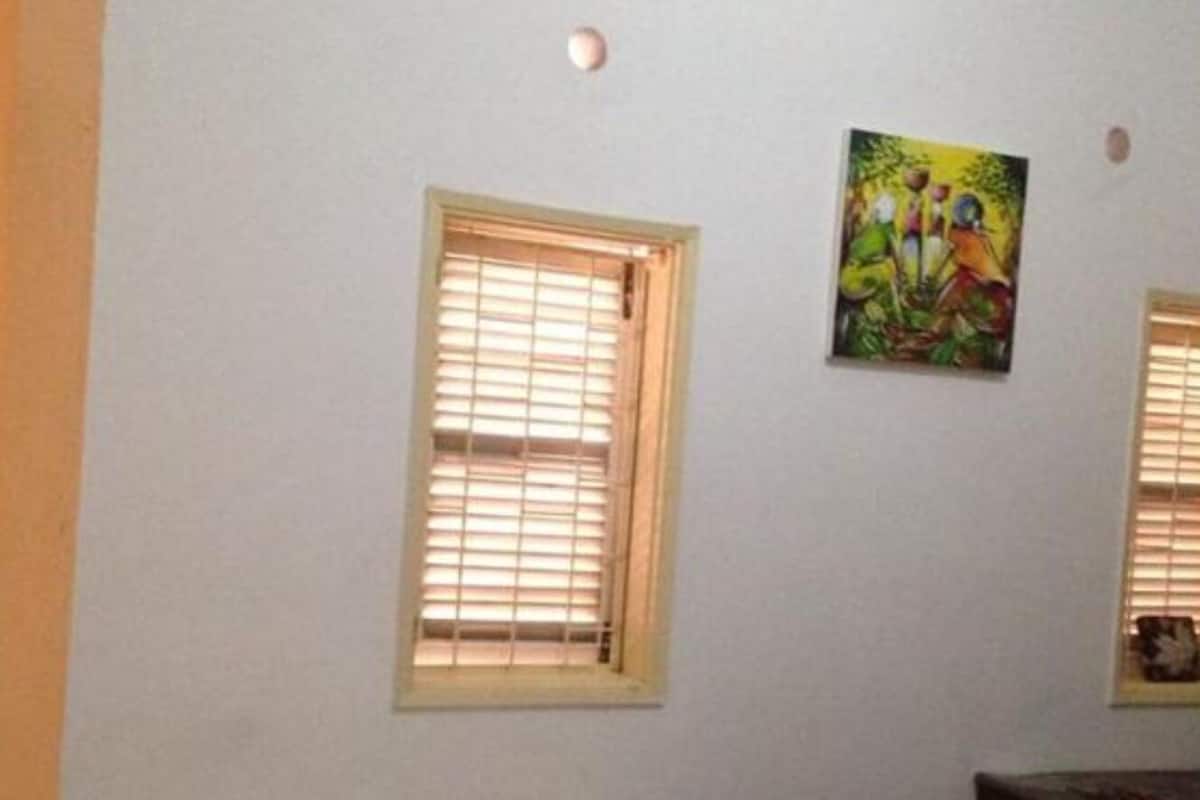 Een kamer met twee ramen, een bed en een schilderij aan de muur.